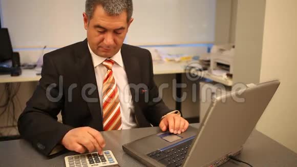 商人在办公室里用笔记本电脑计算视频的预览图