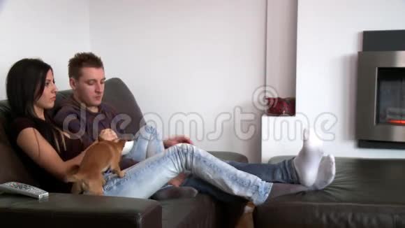 一对活泼的夫妇坐在沙发上看电视视频的预览图