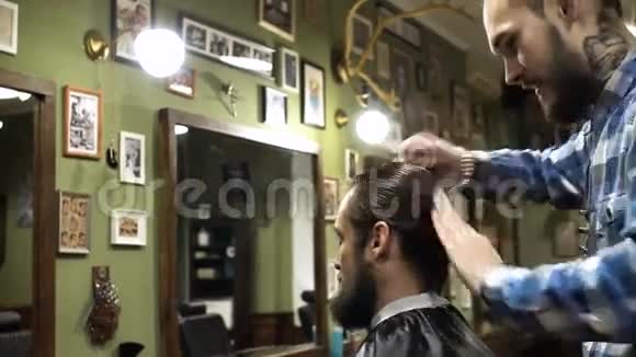长发理发师正在理发店给留胡子的年轻人理发4K视频的预览图