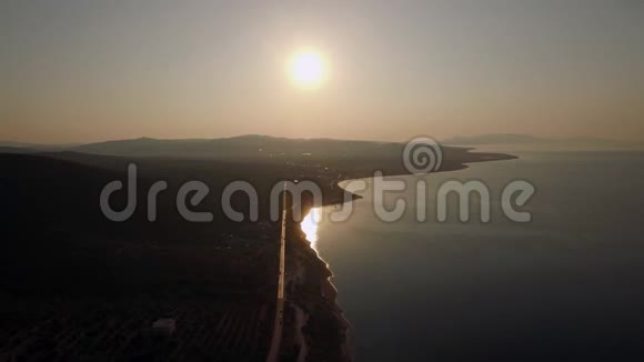 希腊日落时海岸线和绿色高地的空中景象视频的预览图