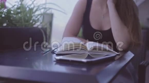 坐在街头咖啡馆里写笔记的漂亮女孩视频的预览图