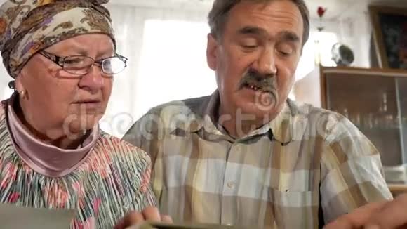 一对老年夫妇正在家里看着他们的旧照片聊天有胡子的男人有老婆的视频的预览图