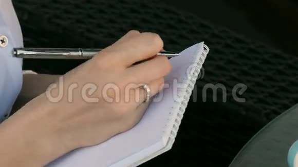 一个女孩在笔记本上写的特写视频的预览图