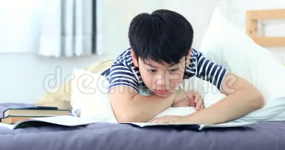 亚洲男孩在床上做作业和看书视频的预览图