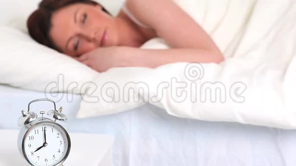 一个可爱的女人睡觉时闹钟响视频的预览图