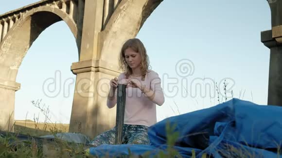 年轻女子在老桥附近收集一个旅游帐篷视频的预览图