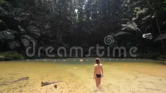 婆罗洲兰比尔山国家公园的热带雨林中女人游进五颜六色的自然游泳池瀑布优美视频的预览图