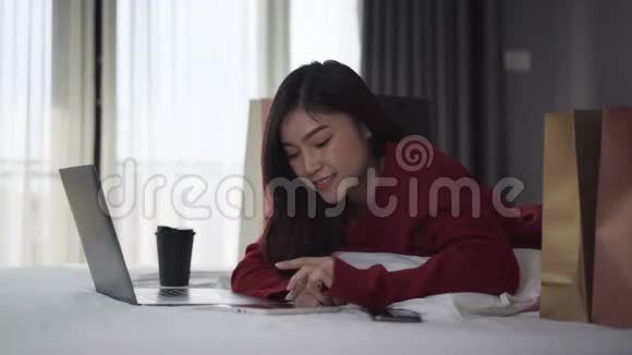 幸福的女人用平板电脑在床上用信用卡进行网上购物视频的预览图