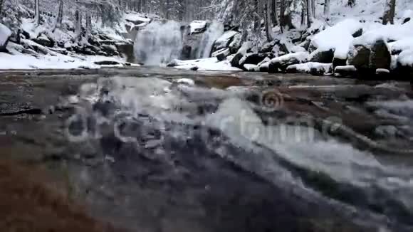冬季的景色从泡沫般的湍急的溪流进入瀑布瀑布水位多云的天空反射深冻视频的预览图