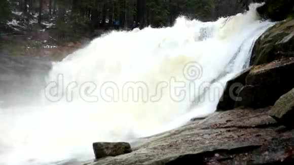 巨大的水流正落入下面泡沫般的池塘森林中的高瀑布山河的水晶水视频的预览图