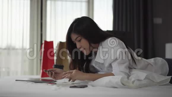 幸福的女人用平板电脑在床上用信用卡进行网上购物视频的预览图
