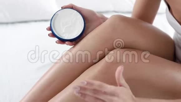 身体皮肤护理女性在卧室涂抹身体霜腿部皮肤视频的预览图