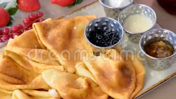 传统的俄罗斯煎饼布里尼提供果酱酸奶油和草莓盘特写镜头视频的预览图