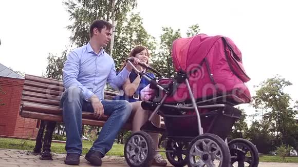 美丽的年轻母亲和一辆婴儿马车在公园里散步视频的预览图