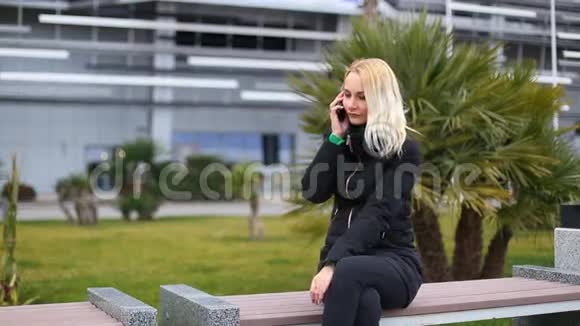 年轻女孩在手机上说话微笑户外快乐的女人视频的预览图