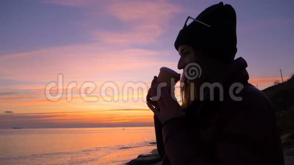 美丽的年轻女孩沿着海滩散步慢慢地走向美丽的日落视频的预览图