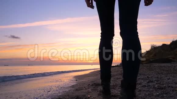 美丽的年轻女孩沿着海滩散步慢慢地走向美丽的日落视频的预览图