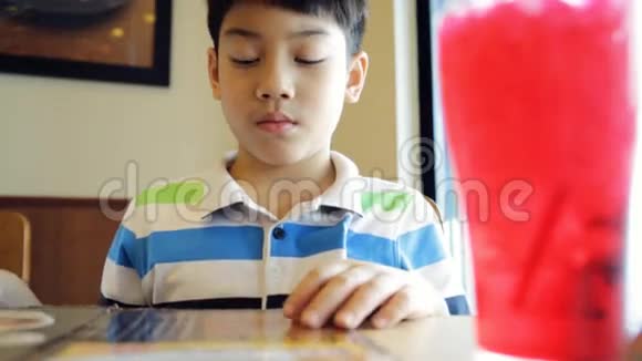 快乐亚洲可爱男孩阅读菜单书和点视频的预览图