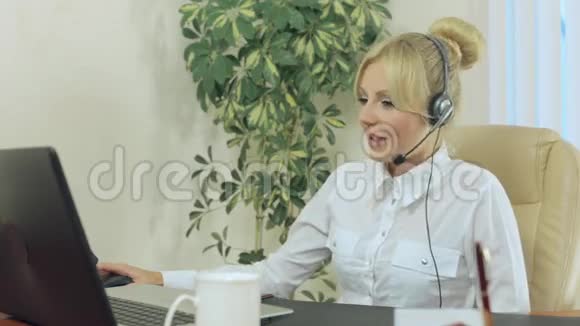 办公室里的金发美女戴着耳机视频的预览图
