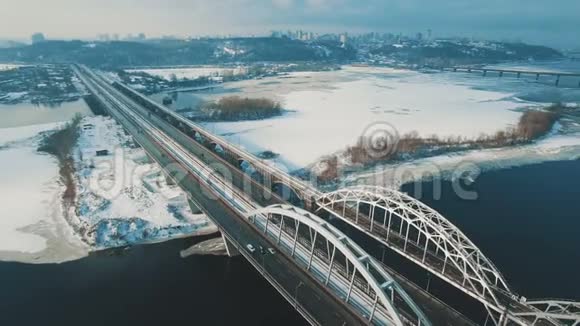 汽车和火车在结冰的河流上空的无人机画面上行驶视频的预览图