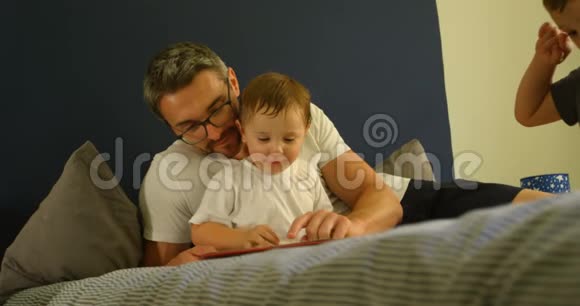 父亲和儿子在床上看书视频的预览图
