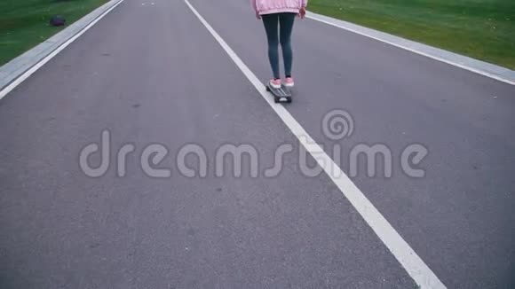 年轻漂亮的金发女郎穿着粉红色的风挡玩滑板滑着长板下山视频的预览图