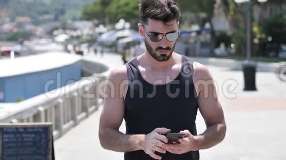 海滩上的年轻人用手机拍海视频的预览图