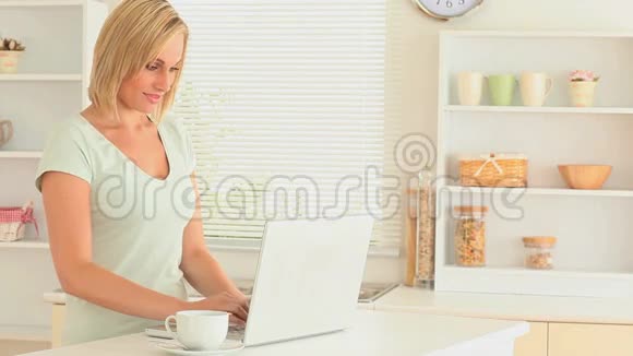 迷人的女人一边喝茶一边用笔记本电脑视频的预览图