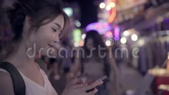 亚洲女性游客背包客微笑并使用智能手机独自旅行户外城市街道视频的预览图