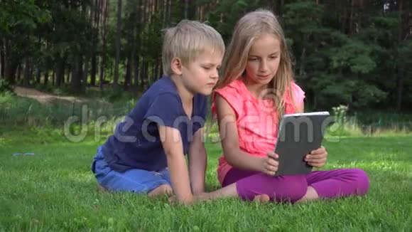 两个孩子在户外玩平板电脑视频的预览图