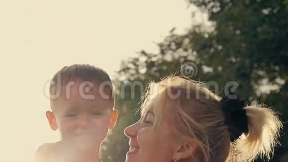 在日落前的傍晚宝宝在花园里和妈妈一起感到快乐和微笑视频的预览图