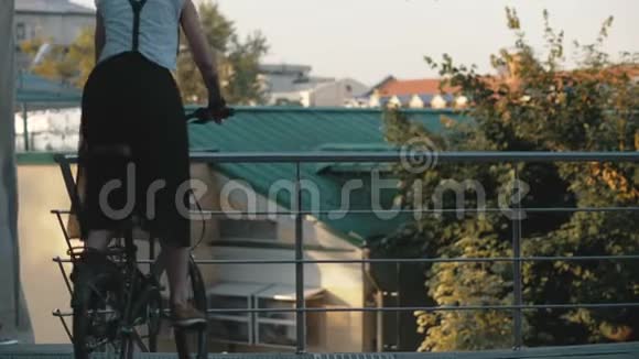 年轻的红发妇女骑自行车在城市带手机的女人视频的预览图