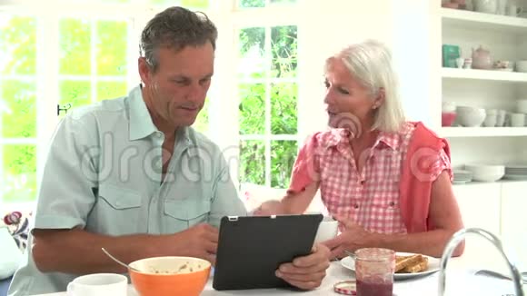 中老年夫妇看着数字平板早餐视频的预览图