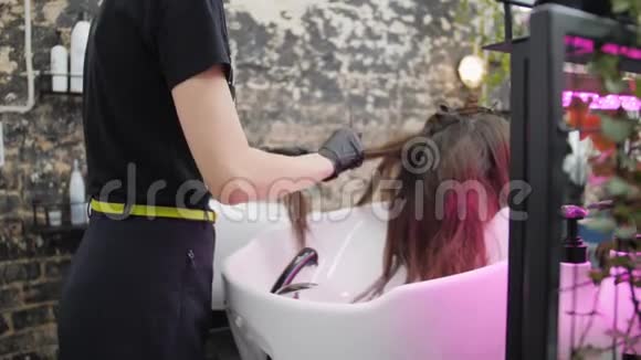 在美容院为女孩做创意发型的专业女性理发师视频的预览图