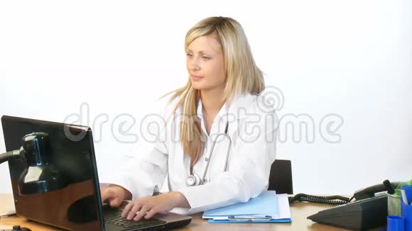 漂亮的金发医生在医院办公室用笔记本电脑视频的预览图