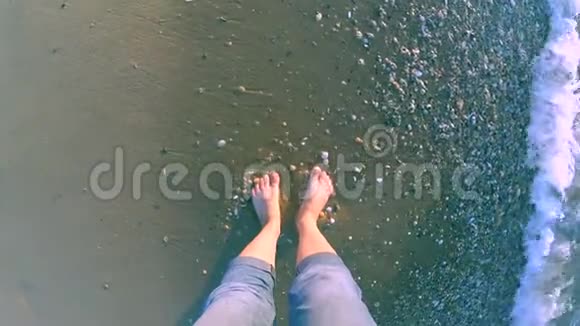 女孩站在海边海浪拍打着她的脚视频的预览图
