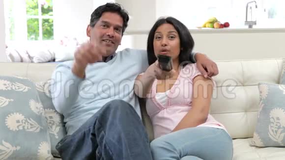 印度夫妇一起坐沙发看电视视频的预览图
