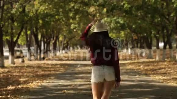 戴帽子的女孩走在远处的一条秋巷里视频的预览图