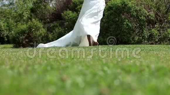新娘穿着婚纱走在草地上视频的预览图