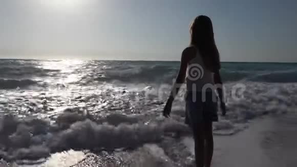 日落时在海滩上玩耍的孩子看海浪的孩子岸上的女孩肖像视频的预览图