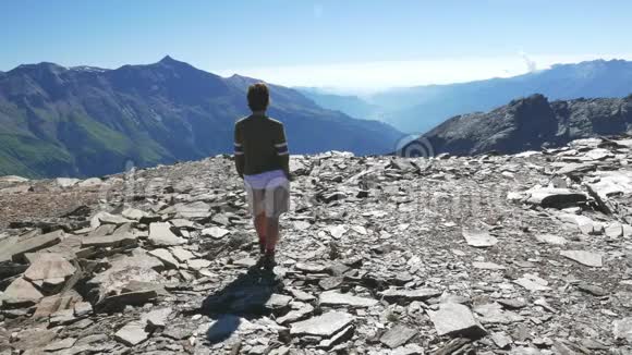 女子行走在高空落基山景观中意大利法国阿尔卑斯山的夏季冒险慢动作视频的预览图
