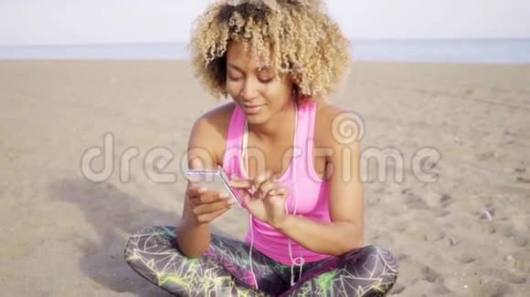 快乐的女人坐在海滩边看着视频的预览图