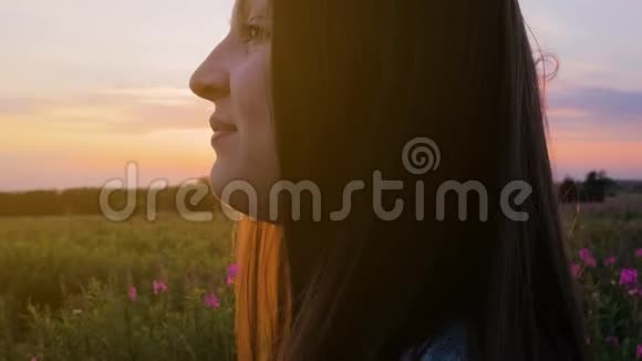 田野里年轻漂亮的女孩看着夕阳近距离射击视频的预览图