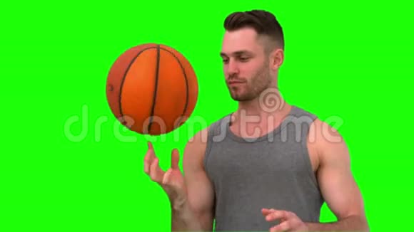 一个人用手指在绿色背景上旋转篮球视频的预览图
