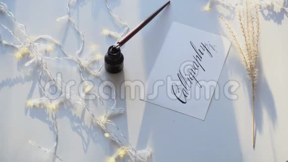 美丽的明信片黑色墨水在白纸上的书法铭刻在光桌上的花环上视频的预览图