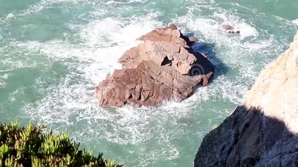 巨大的石头在岸边小波溅在一块大石头上视频的预览图