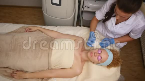 一个漂亮的女人闭着眼睛躺在美容师的桌子上皮肤科医生专业地清洁了她的脸视频的预览图