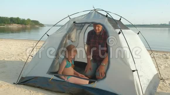 一个成熟的人在海边的户外度假时收集帐篷视频的预览图
