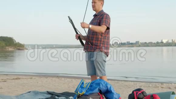 一个成熟的人在海边的户外度假时收集帐篷视频的预览图