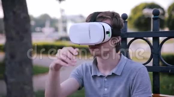 年轻的帅哥在城市公园里戴着虚拟现实护目镜视频的预览图